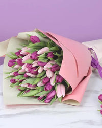A stunning bouquet featuring 26 vibrant purple tulips and 25 charming pink tulips, beautifully wrapped in dual-colored paper.