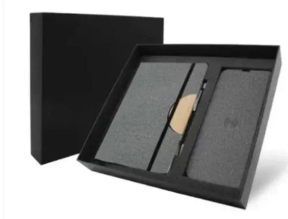 Black gift box containing A5 notebook, black pen with stylus tip, and wireless charging pad.