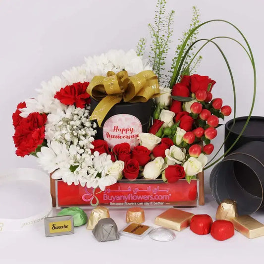 Smiling couple celebrating their anniversary with the flower and chocolate arrangement.