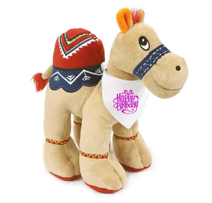 Adorable beige camel plush, 25cm tall, wearing a pink "Happy Birthday" bandana. Super soft and cuddly with recycled filling.