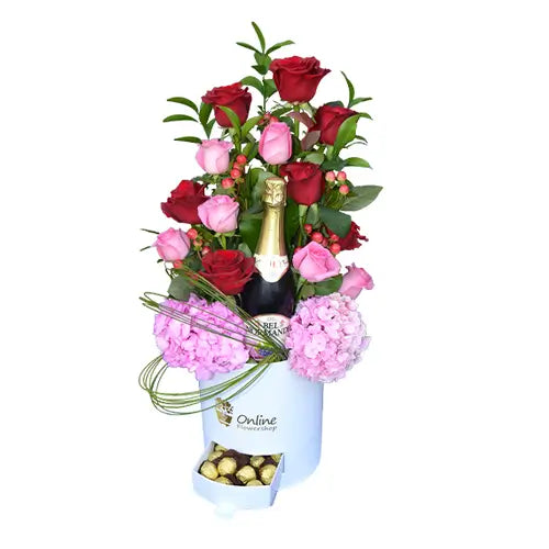 Gift box with red and pink roses, and a bottle of sparkling red grape juice.