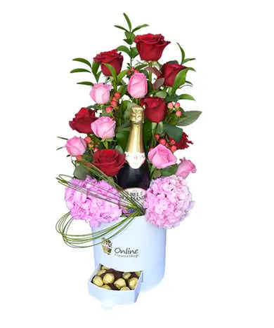 Gift box with red and pink roses, and a bottle of sparkling red grape juice.