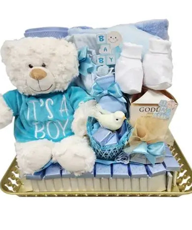 Photo of a beautifully arranged baby gift set with chocolates, a soft teddy bear, baby essentials in pink or blue, and a decorative tray.