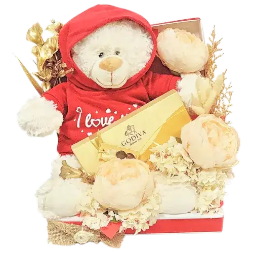 a romantic gift set featuring a box of Godiva chocolates, a soft teddy bear with an "I Love You" hoodie, and a beautiful arrangement of artificial gold flowers, cream peonies, and dried florals