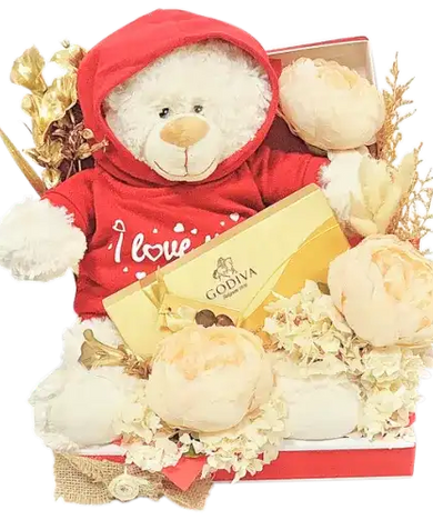a romantic gift set featuring a box of Godiva chocolates, a soft teddy bear with an "I Love You" hoodie, and a beautiful arrangement of artificial gold flowers, cream peonies, and dried florals.