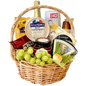 A photo of a wicker gift basket overflowing with a variety of cheeses, grapes, nuts, crackers, a jar of chutney, a bottle of sparkling grape juice, and small hazelnut snacks.