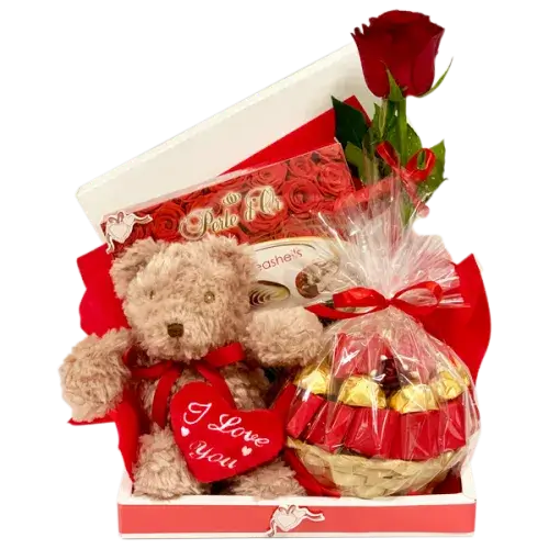 Photo of a romantic gift set featuring a red rose, a box of Belgian chocolates, and a soft teddy bear, perfect for expressing love