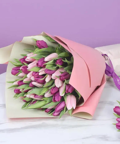 A stunning bouquet featuring 26 vibrant purple tulips and 25 charming pink tulips, beautifully wrapped in dual-colored paper.