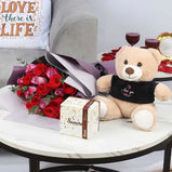 Person receiving the flower, chocolate, and teddy bear gift, expressing delight and surprise.