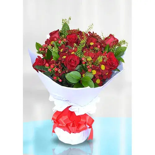 Red rose bouquet with red chrysanthemums and hypericum in a vase.