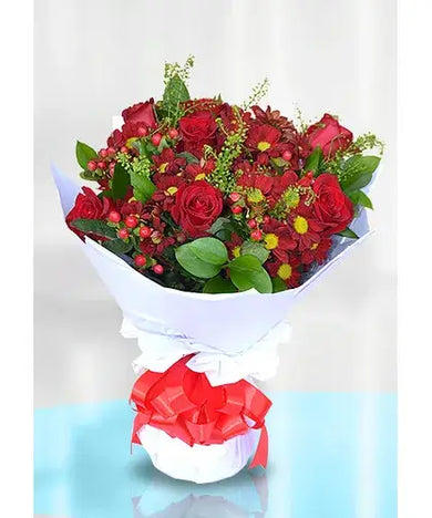 Red rose bouquet with red chrysanthemums and hypericum in a vase.