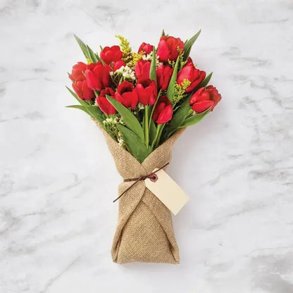 Hand-tied bouquet of 15 red tulips with white accents.