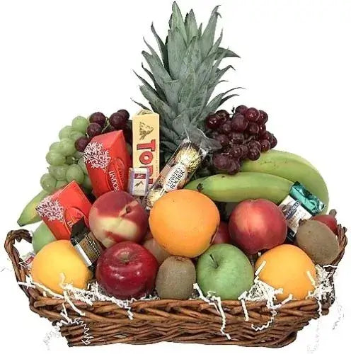 A photo of a wicker gift basket overflowing with colorful fruits and a variety of popular chocolate bars.
