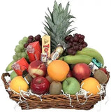 A photo of a wicker gift basket overflowing with colorful fruits and a variety of popular chocolate bars.