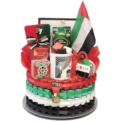 Large gift basket wrapped in cellophane with UAE ribbons, containing chocolates, mug, scarf, flag, pin badges, and gift boxes.