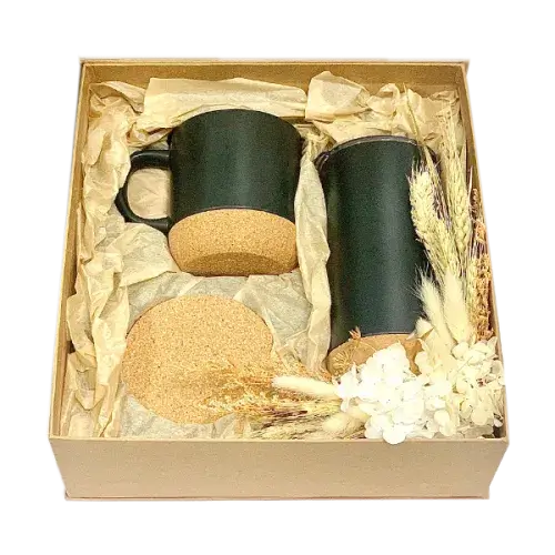 Cardboard gift box containing black mugs with lids, black tumbler with cork bottom, and cork coaster.