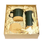 Cardboard gift box containing black mugs with lids, black tumbler with cork bottom, and cork coaster.