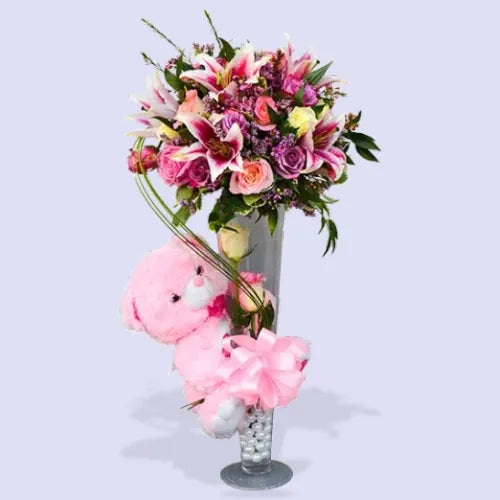 Charming Lady Bouquet with pink lilies, purple and peach roses, pink teddy, and pearls inside the vase.