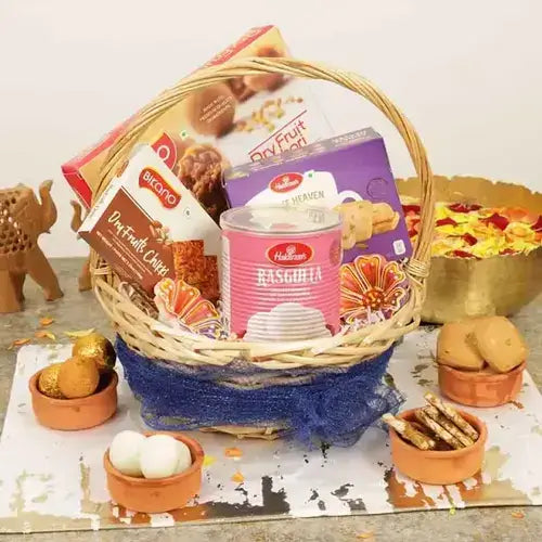 Dry fruit gift basket with Rasgulla, dry fruit kachori, chikki, cookies, and designer diya in a white basket, available online in Dubai, UAE from Giftshop.ae