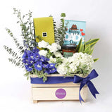 a Father's Day gift hamper with a wooden box overflowing with blue and white flowers, Patchi chocolates, a greeting card, and a scented candle