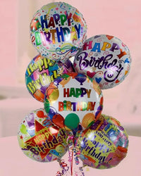 A bunch of 6 colorful Happy Birthday foil balloons filled with helium and tied with ribbons.