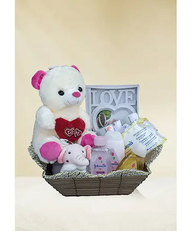 Photo of a premium baby gift hamper filled with Johnson & Johnson baby care products, soft towels, a photo frame, and two soft toys.