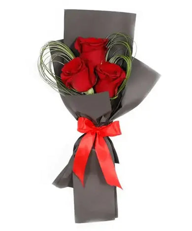 Three red roses with filler in black wrapping with a ribbon bow, paired with a decadent fudge cake (Timeless Love Gift Set - giftshop.ae)