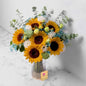 Bright sunflower and rose bouquet in Dubai, featuring fresh sunflowers, white and yellow roses, eucalyptus, and baby breath in a glass vase.